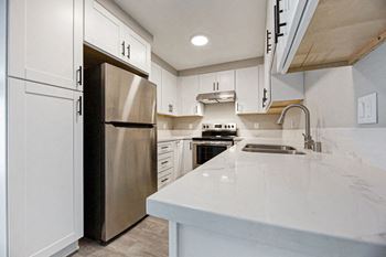 A kitchen with white cabinets and a stainless steel refrigerator